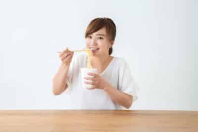 カップ麺を食べる女性