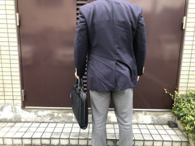 玄関に立つスーツの男性