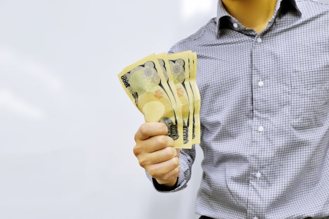 数枚の紙幣を手に持つ男性