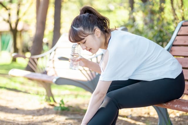 ベンチで足首をさする若い女性